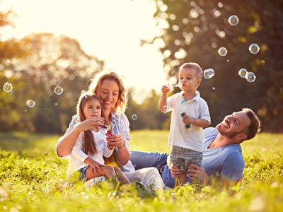 Happy family with a child blowing bubbles in a sunny park