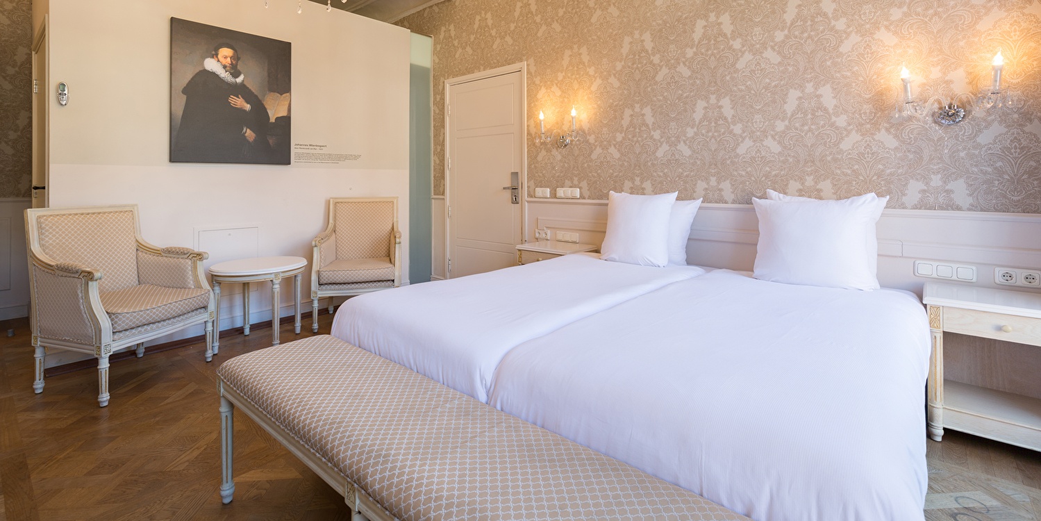 Hotel room at Amrâth Hotel Bigarré with double bed (twin setup), bench and seating area.