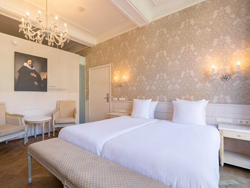 Hotel room in Amrâth Hotel Bigarré with double bed (twin setup), small bench and seating area.