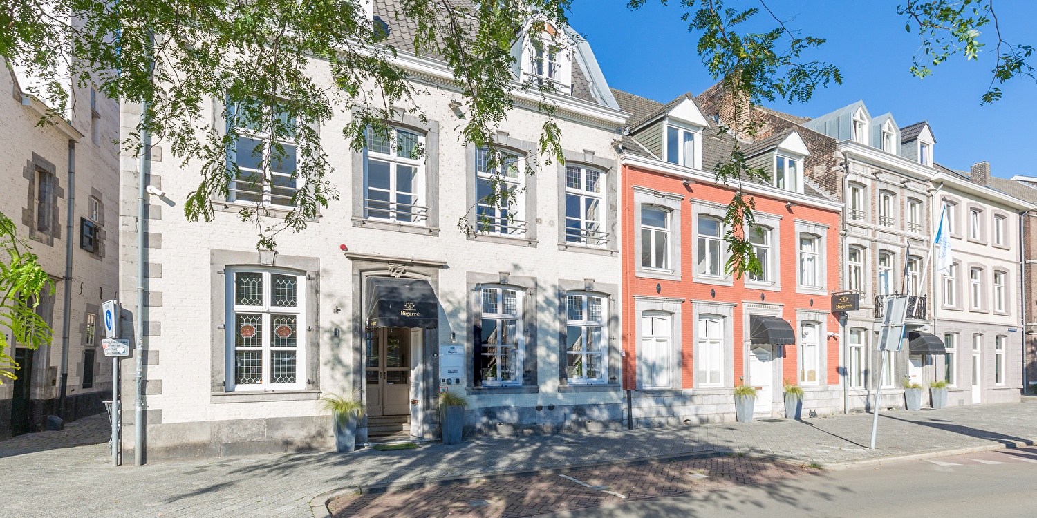 Frontseite des Amrâth Hotel Bigarré in Maastricht, historisches Gebäude mit weißen und roten Fassaden in einer Reihe von Herrenhäusern.